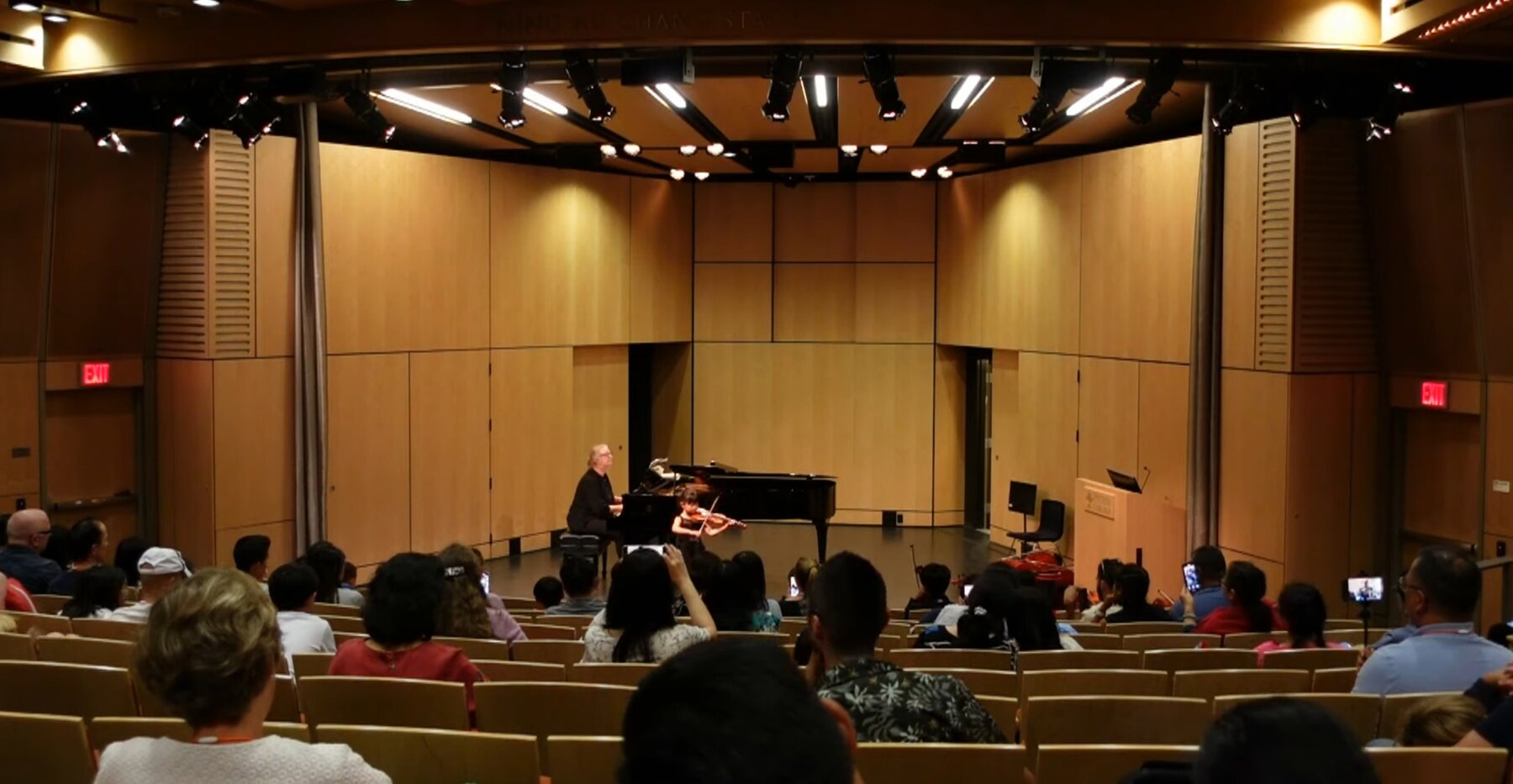 Hailey Murata performing violin with piano accompaniment in an auditorium