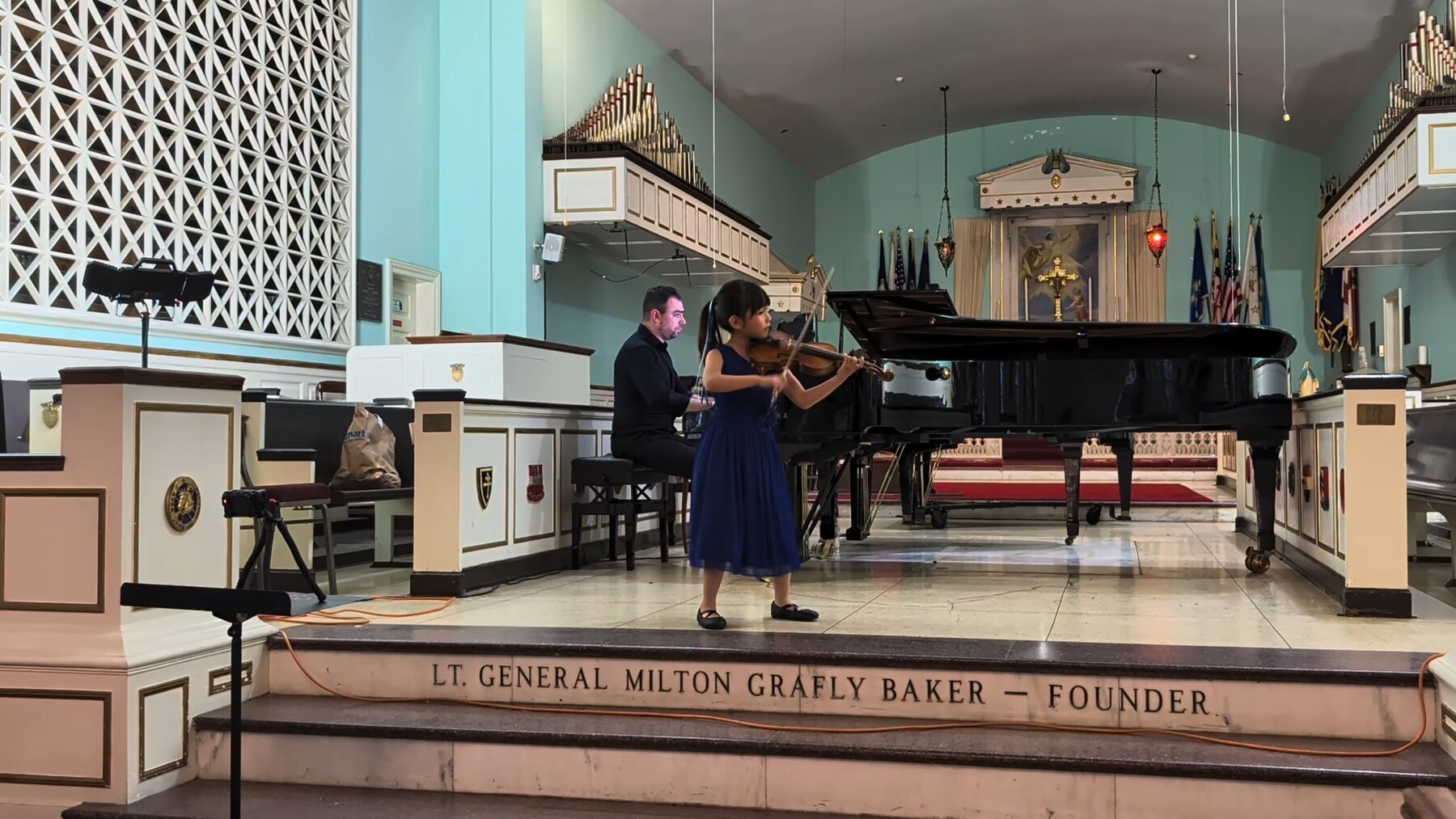 Hailey Murata performing violin in a blue dress with piano accompaniment