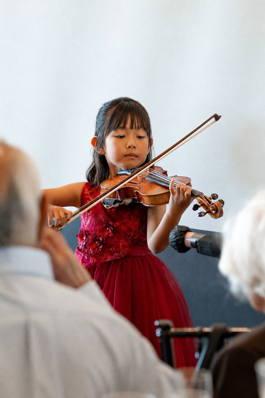 Hailey Murata performing violin in a red dress